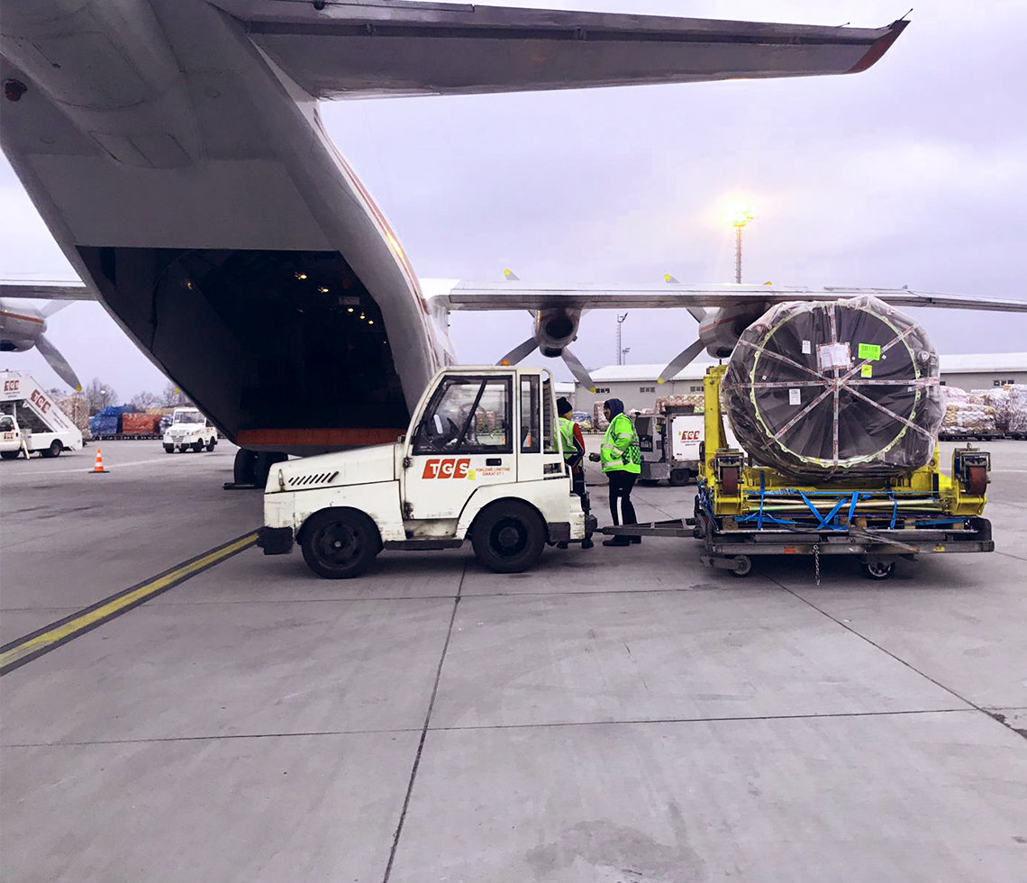 Antonov AN-12 cargo charter aircraft rear door open with crew loading freight