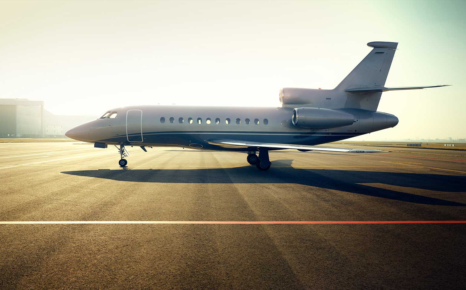 Dassault Falcon 900 private jet charter sitting on runway during sunrise