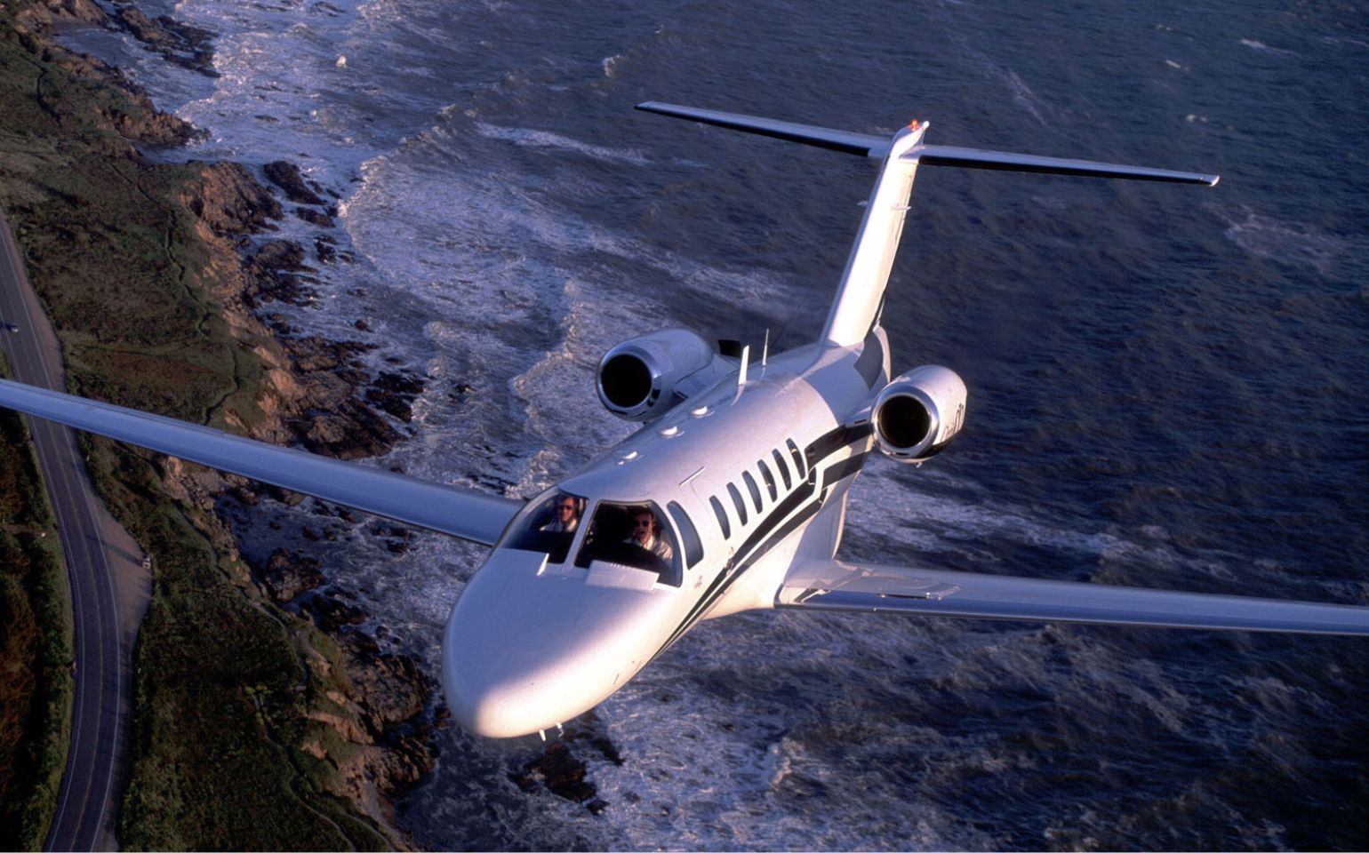 Citation CJ2 private jet flying over the sea with two pilots on board