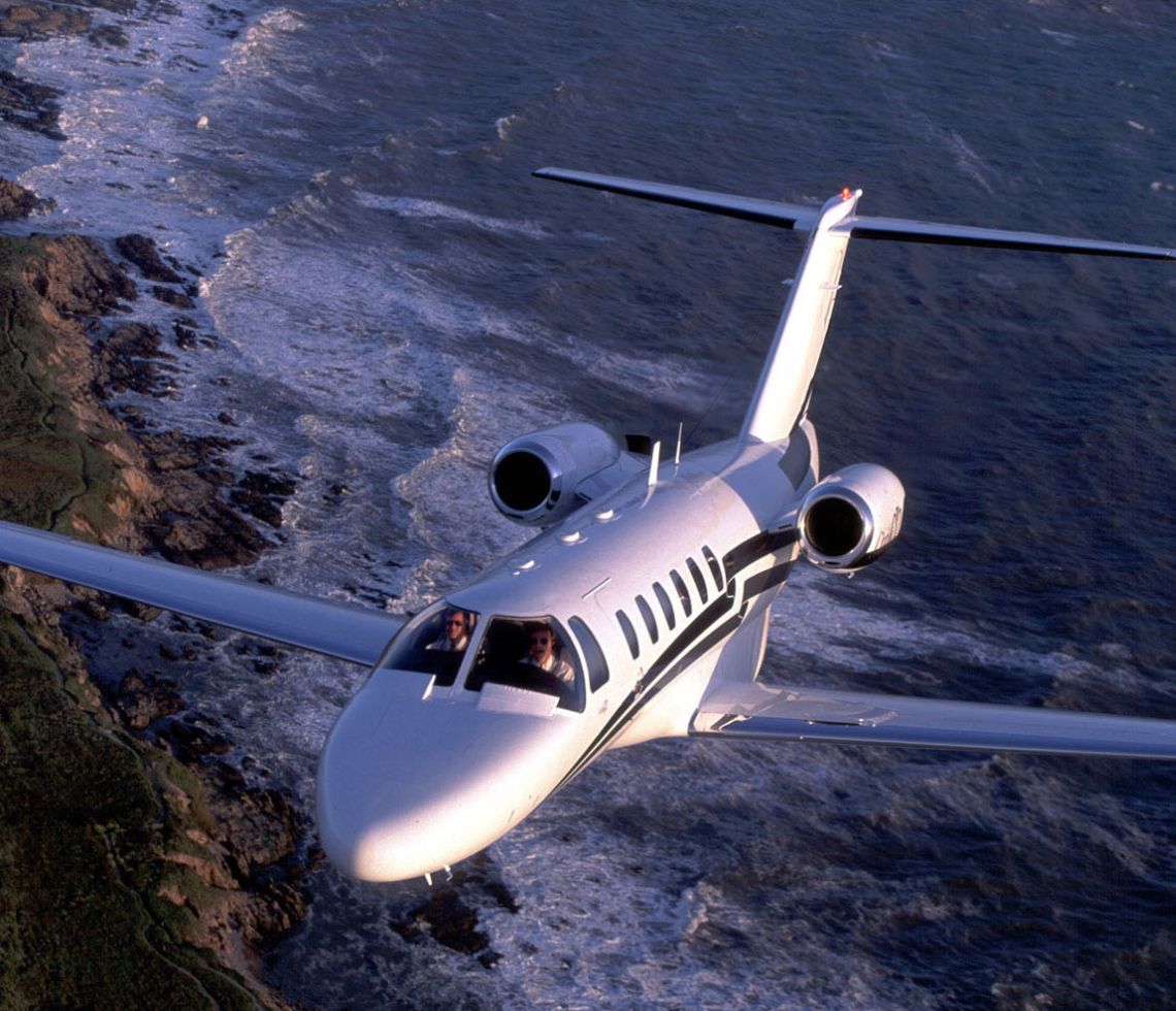 Citation CJ2 private jet flying over the sea with two pilots on board