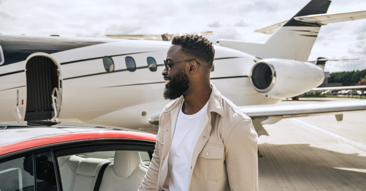Man leaving private jet and getting into the back of a red car