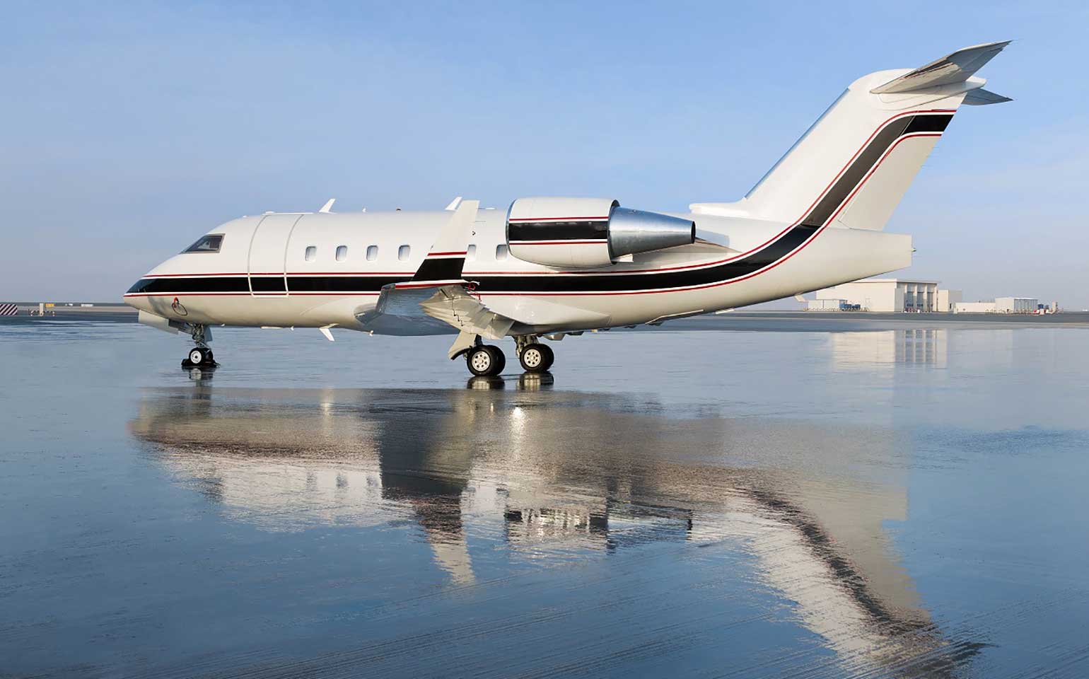 Bombardier Challenger 604 private jet on airport runway with reflection