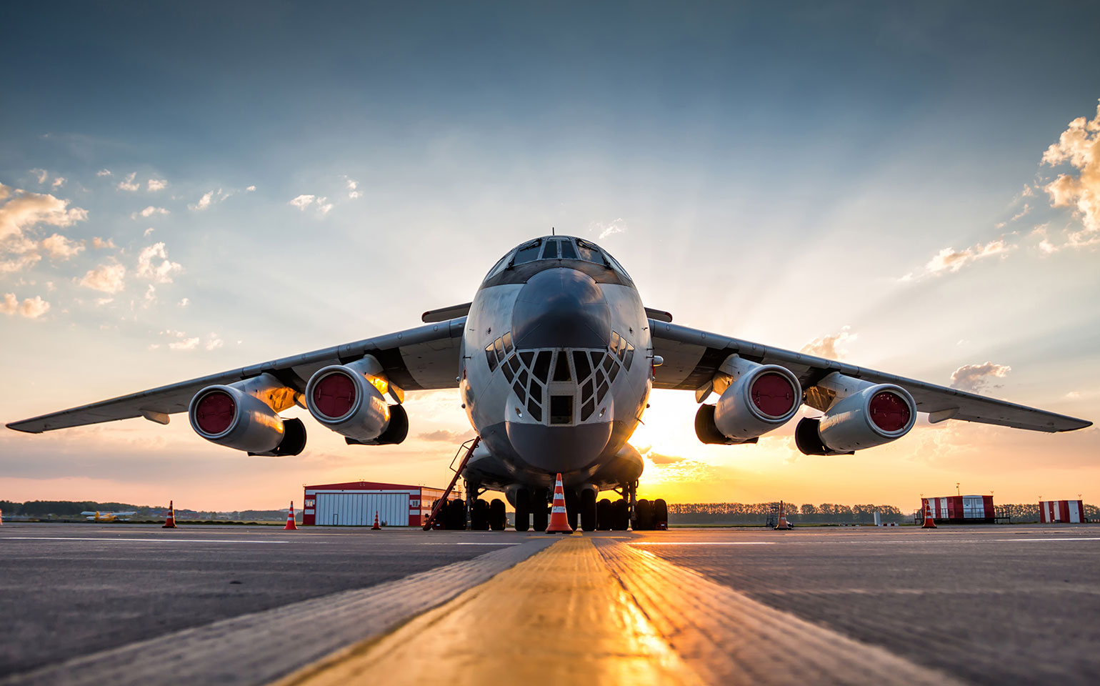 Lockheed C-130 Hercules cargo charter plane sitting on runway during sunset